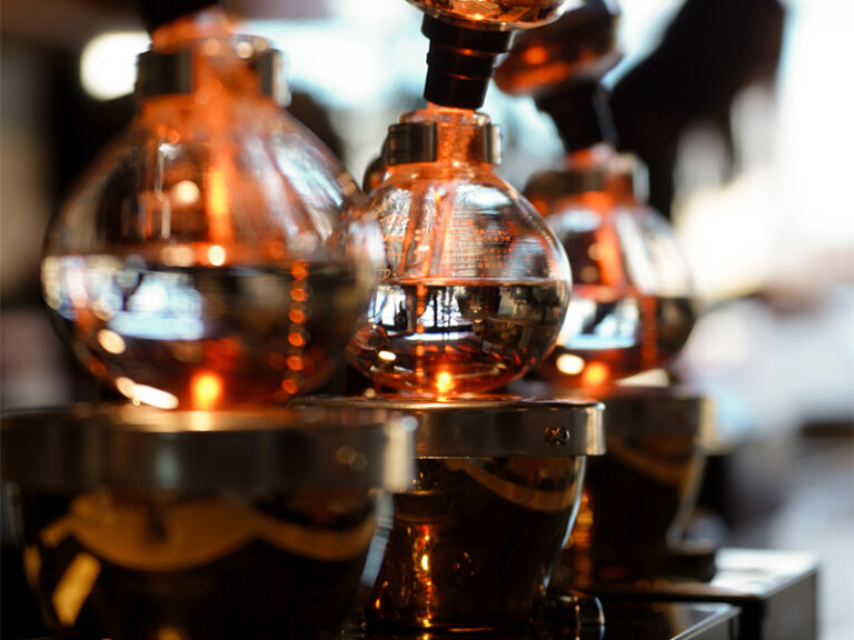 温かい照明の中、サイフォンで丁寧に淹れられるclastaのホットコーヒー