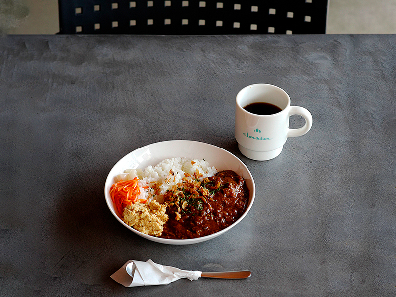 白いお皿に盛りつけられた「パイカカレー」。濃い茶色のルーの中には、じっくり煮込まれてとろけるように柔らかくなった豚バラ軟骨（パイカ）がゴロゴロと入っており、白ごはんと一緒に提供されている。付け合わせには彩りのよい野菜も添えられ、食欲をそそる盛りつけ。