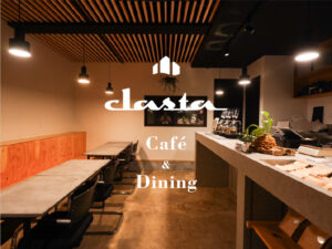 落ち着いた照明が灯るクラスタ店内。木のテーブルにグラスや料理が並び、夜ならではの温かみある雰囲気を演出している様子。