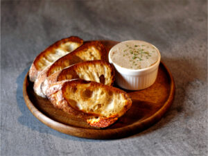 木のお皿にバゲットと盛り付けられているレバーパテ