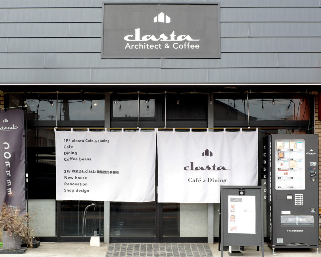 Clasta Café & Dining の外観。白いのれんにロゴが入り、1階はカフェ、2階は建築設計事務所の案内が書かれている。Architect & Coffee のサインが掲げられている店舗外観。